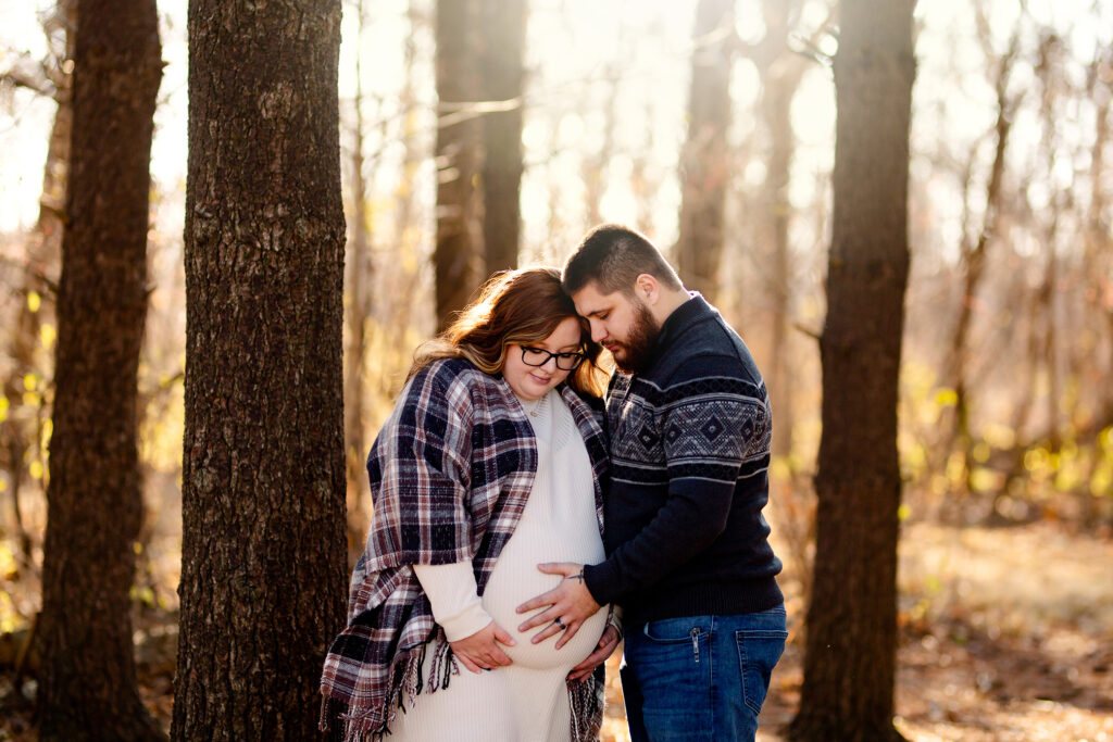 Couple is posed in the woods to celebrate pregnancy and upcoming baby