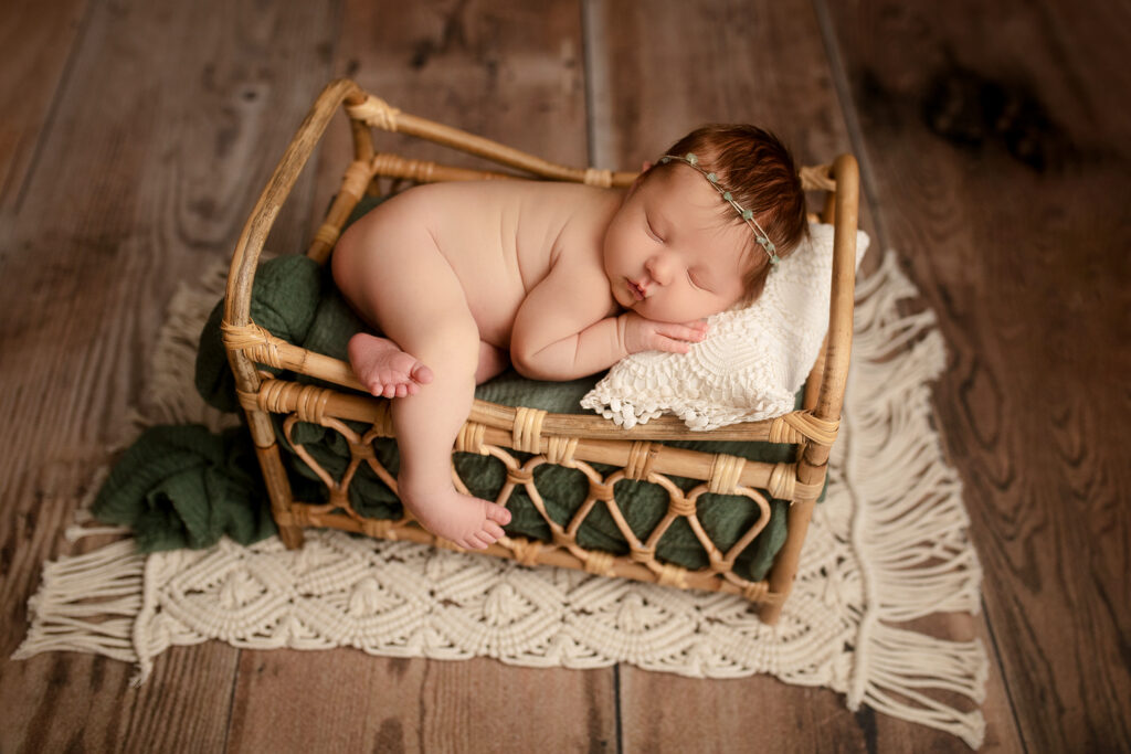 Newborn baby girl sleeps on her tummy decorated in green
