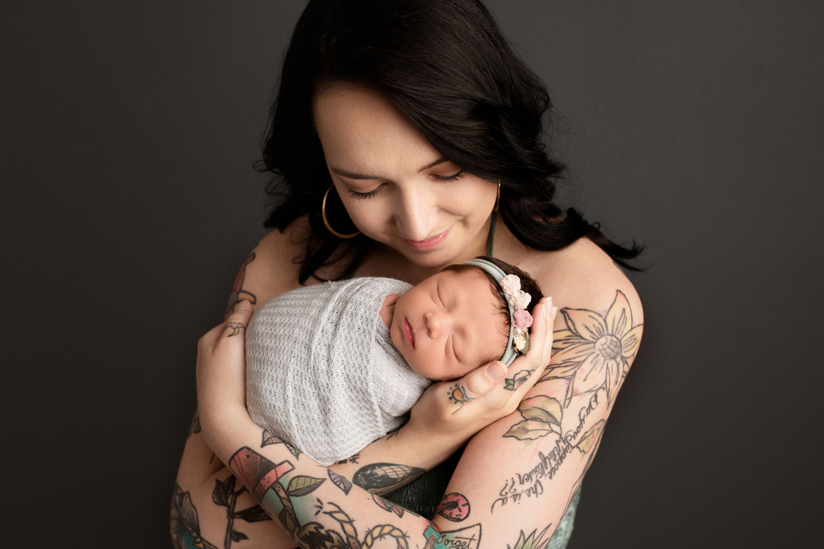 Mother holding Newborn Baby Girl with Tattoos on her arms