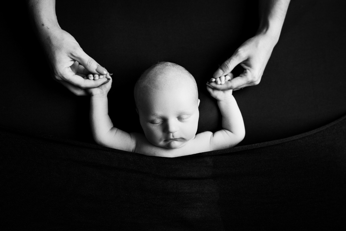 Newborn Baby Boy Holding Mom's hands in Black and White