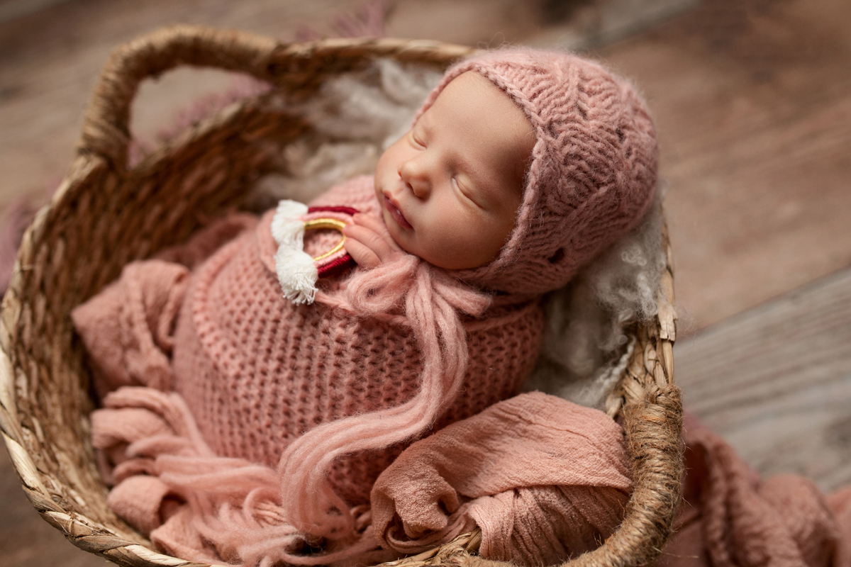Baby Girl in Pink Wrap and Bonnet Holding Little Rainbow in a Basket