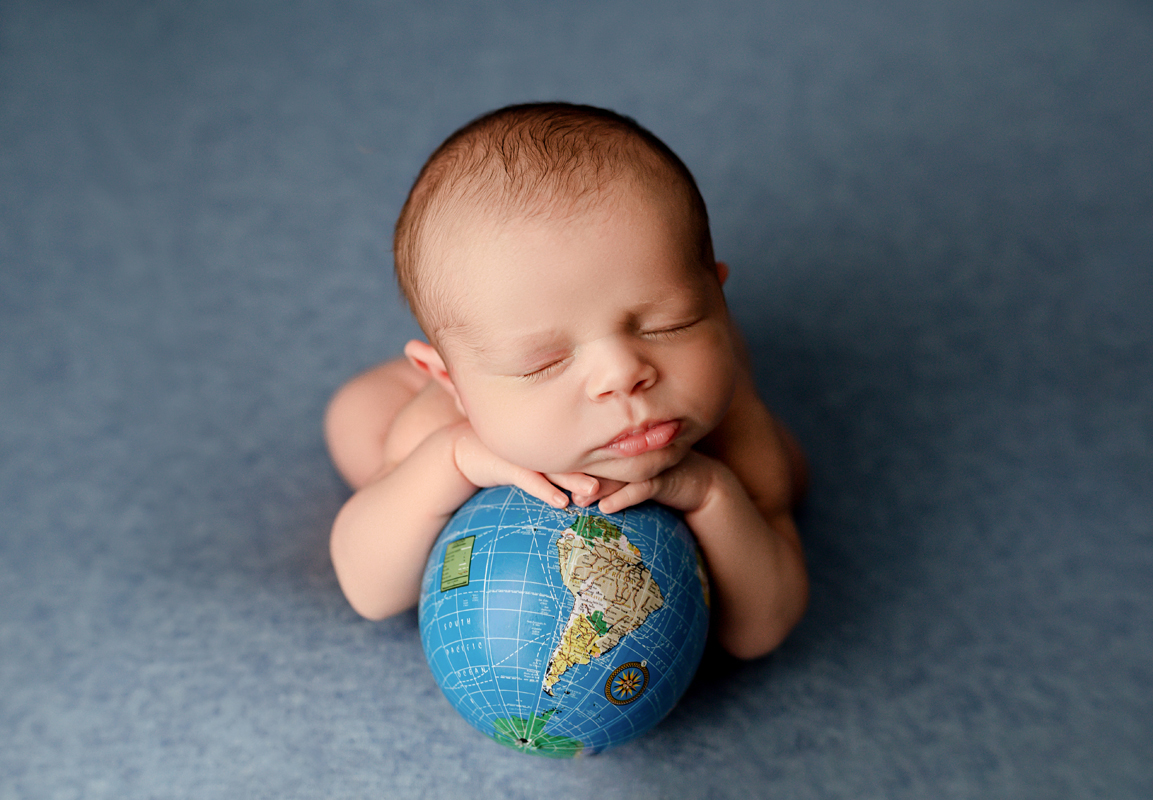 Newborn Baby Boy Named Atlas Posed on Little Globe on Blue Backdrop