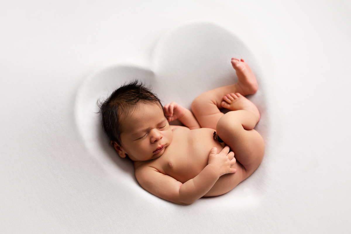 Newborn Baby Boy is Curled up in a White Heart