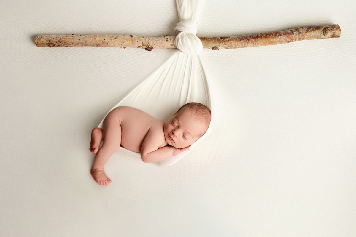 Baby boy hangs from a stick on a white background