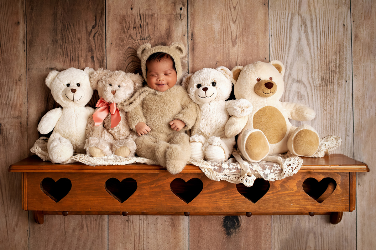 Baby girl smiles in a bear costume on a shelf
