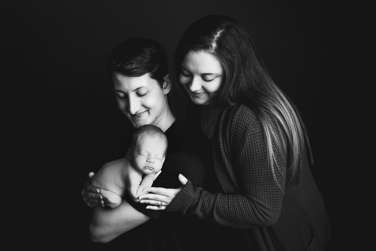 Couple poses with new baby boy during their newborn photo session