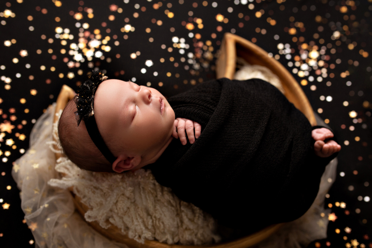 Baby girl sleeps in a moon with sparkles and stars wearing black