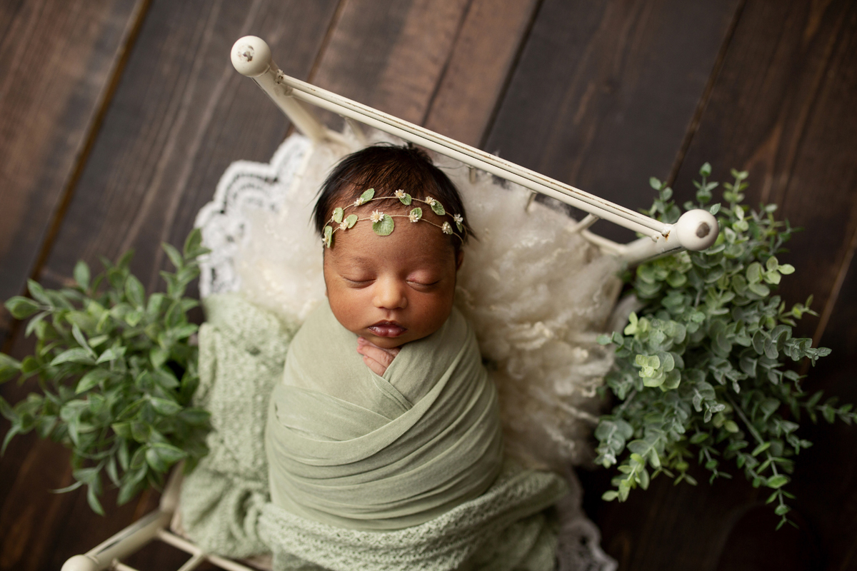 Newborn Girl on White Bed Wrapped in green with Green Leaf Headband